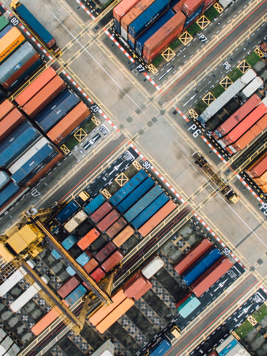 Aerial view of a container port with stacked shipping containers and orange cranes